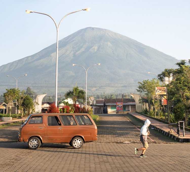 Young man jogging in Central Java with Mount Sumbing in the back