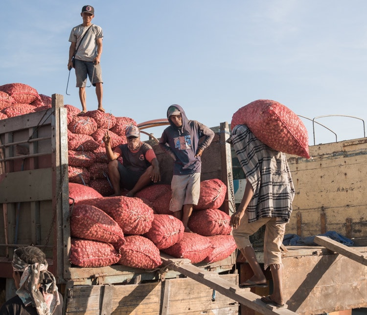Workers carrying sacks of onions to a truck in Makassar, Indonesia