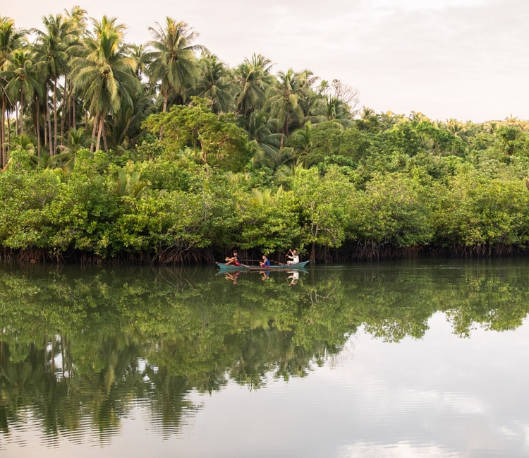 Three boys canoeing back home in Siargao island, Philippines