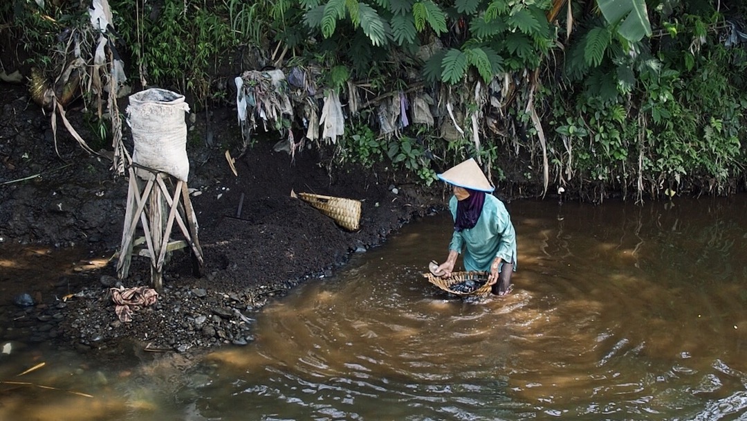 Tuwari is collecting sand from the river bottom to sell it as building material