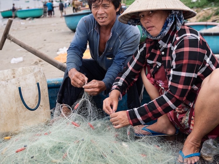 Husband and wife sorting out their fishing net in Mui Ne fishing village, Vietnam